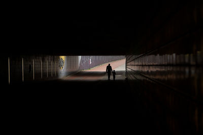 Silhouette man walking on road in city