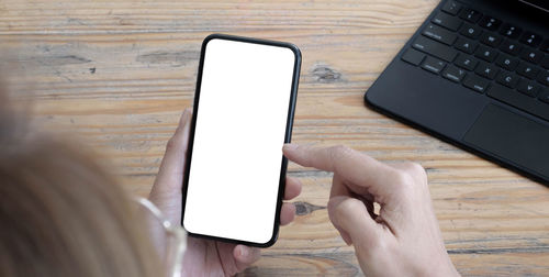 Low section of person using mobile phone on table