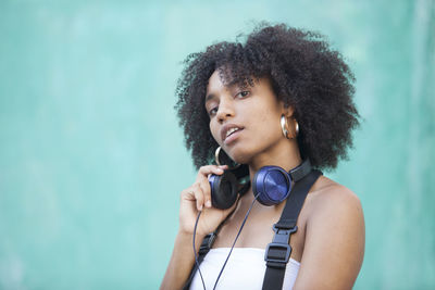 Portrait of young woman with curly hair against blue background