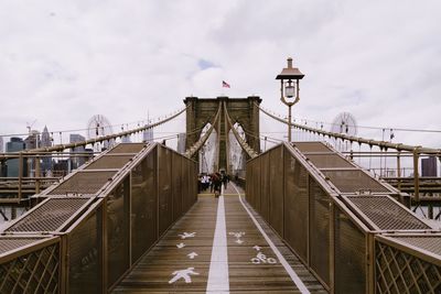 Footbridge against cloudy sky