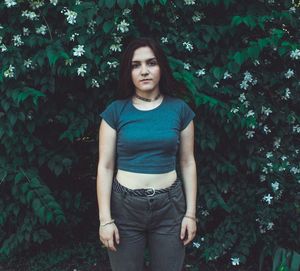 Portrait of beautiful young woman standing against trees