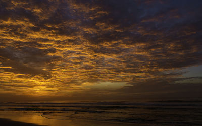 Scenic view of sea against dramatic sky during sunset