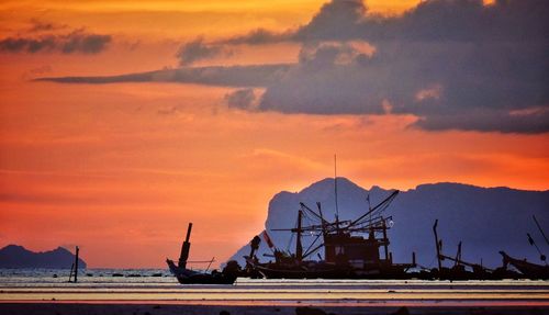 Silhouette boats on sea against cloudy sky during sunset