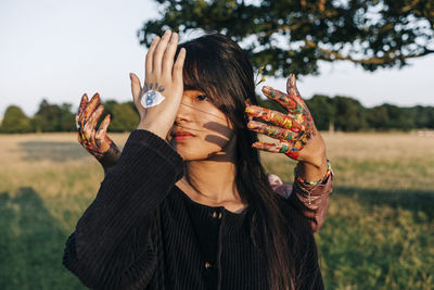 Female friends with painted hands at park during sunset