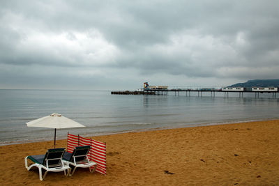 Chairs on beach against sky