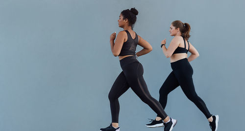 Side view of woman exercising against blue background