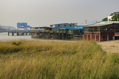 Scenic view of field by buildings against clear sky