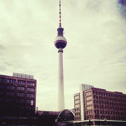 Communications tower in city against sky