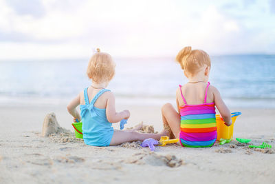 Rear view of boys sitting on beach