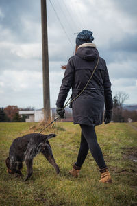 Candid portrait of a woman in winter clothes and bohemian wire-haired pointing griffon 