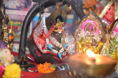 Close-up of lit diya and idol figurines in temple