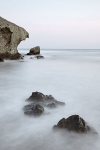 Scenic view of rocks in sea against sky