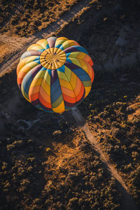 Top-down view of a colorful hot air balloon flying over a desert landscape in rural nevada