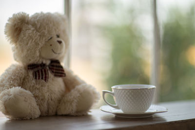 Close-up of teddy bear and coffee cup on table