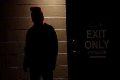 Rear view of silhouette man standing against wall