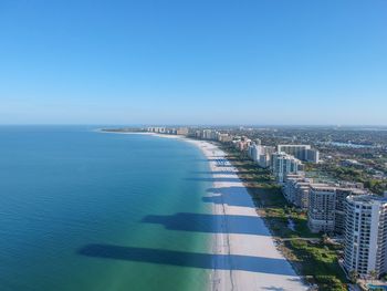 High angle view of sea and buildings against clear sky