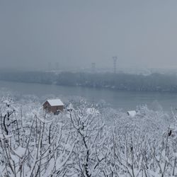 Scenic view of snow covered house by building against sky