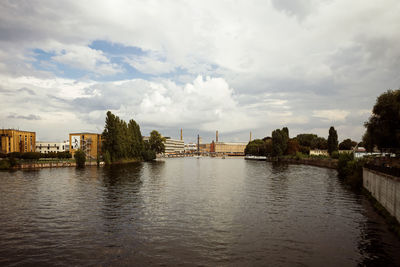 Scenic view of river by buildings against sky