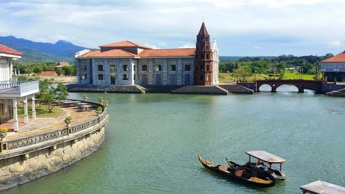 Boats moored in river against buildings