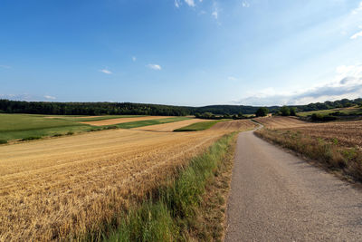 Road amidst field against sky