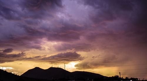 Silhouette mountain against dramatic sky during sunset