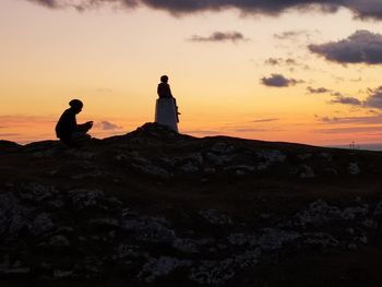 Silhouette people looking at sea against sky during sunset