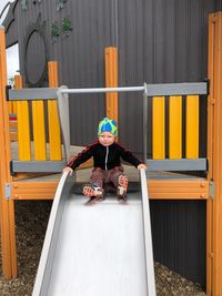 Portrait of boy sitting on slide at playground