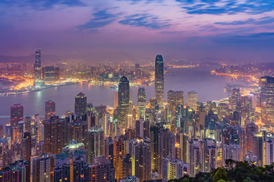 Illuminated modern buildings in city against sky at night