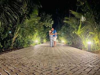 Rear view of man walking on footpath at night