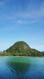Scenic view of sea and mountains against blue sky