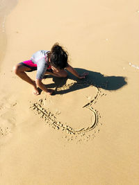 High angle view of woman sitting on sand at beach