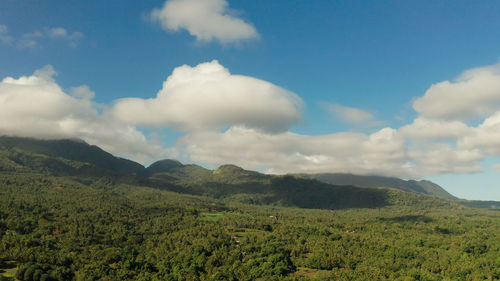 Mountains covered rainforest, trees and blue sky with clouds, aerial view. camiguin, philippines.