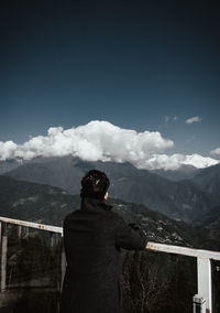 Rear view of man standing on mountain against sky