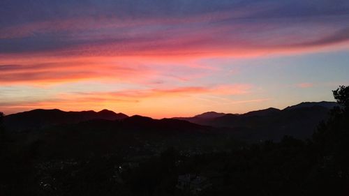 Scenic view of silhouette mountains against orange sky