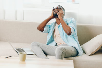 Young woman using phone while sitting on sofa at home