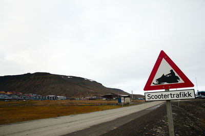 Road signs by mountain against sky