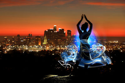 Man and illuminated cityscape against sky at night