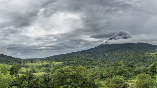 Scenic view of green mountains against cloudy sky