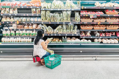 Full length of woman sitting at store