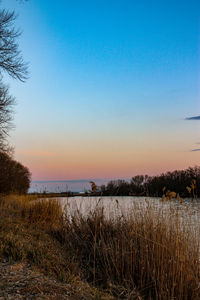 Scenic view of lake against clear sky at sunset