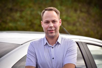 Portrait of young man standing in car