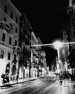 People on city street amidst buildings at night