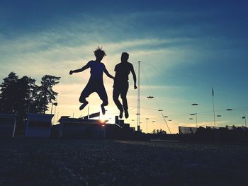 Low angle view of woman jumping against clear sky