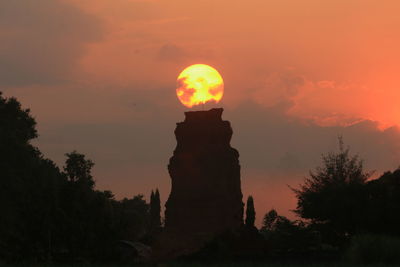 Low angle view of silhouette trees against orange sky