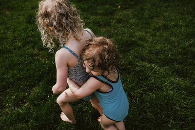 High angle view of wet girl embracing sister at yard