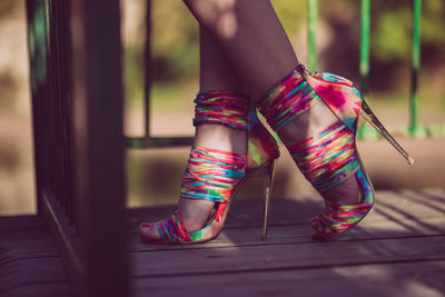 Low section of woman wearing colorful stilettos