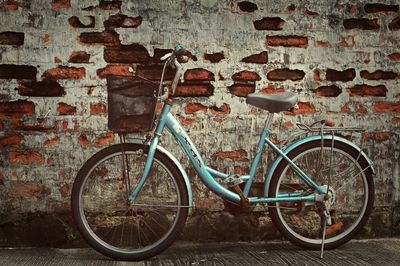 Bicycle parked against brick wall