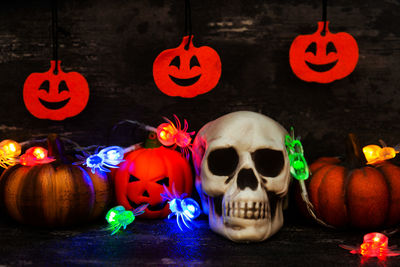 Pumpkins and human skull with illuminated lights on table during halloween