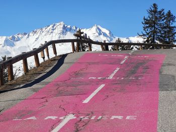 Road by snow covered mountain against sky