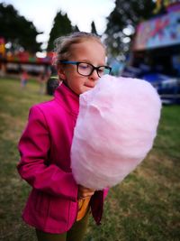 Girl holding candy floss while standing on field